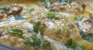 Creamy garlic chicken with herbs and sun-dried tomatoes in a skillet. Perfect savory dinner recipe.